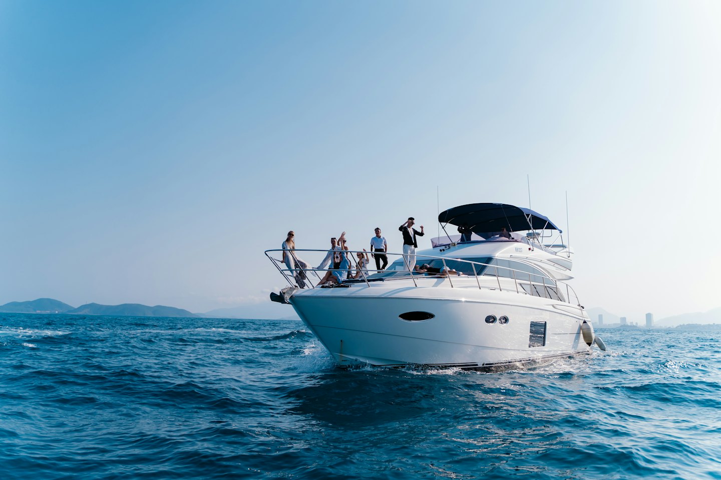 Persone rilassate sul ponte di uno yacht bianco in mare.
